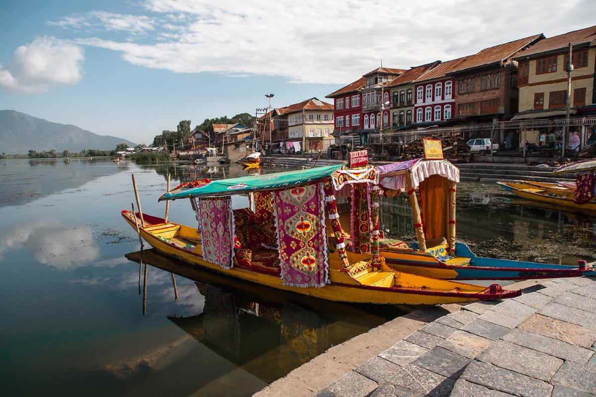 A decorated shikara on the water at Srinagar with old houses behind